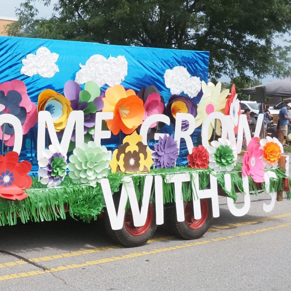 Colorful “Come Grow With Us” parade float covered in oversized flowers and bright decorations participating in the Kiwanis Independence Day Parade in LaPorte, Indiana.