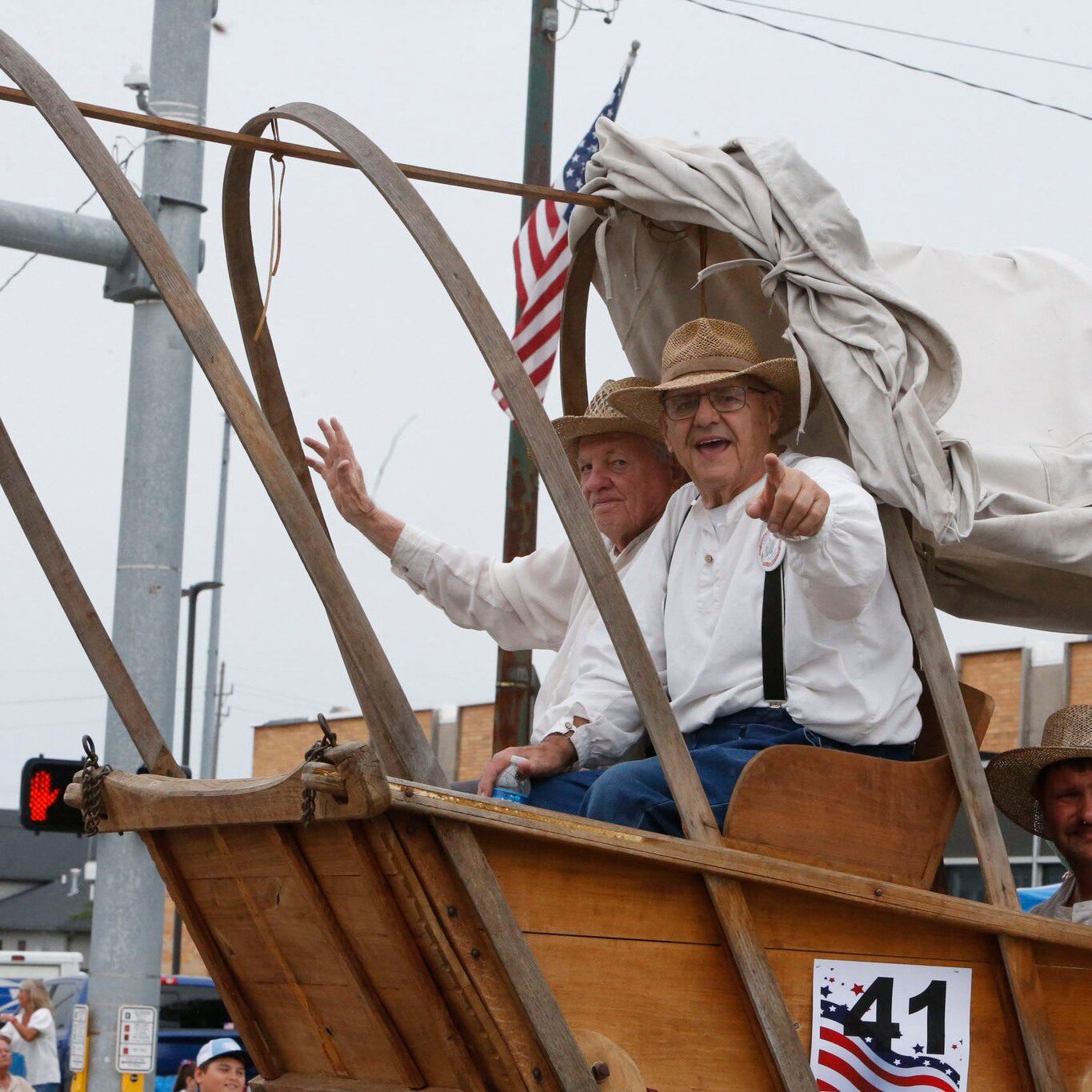 Two men riding in a historic covered wagon float wave to the crowd during the Kiwanis Fourth of July Parade in downtown LaPorte, Indiana.