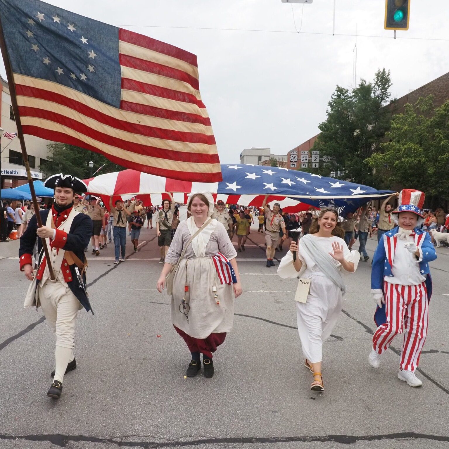 Participants dressed as Revolutionary War soldiers, the Statue of Liberty, and Uncle Sam carry a large American flag during the Kiwanis Independence Day Parade in LaPorte, Indiana.