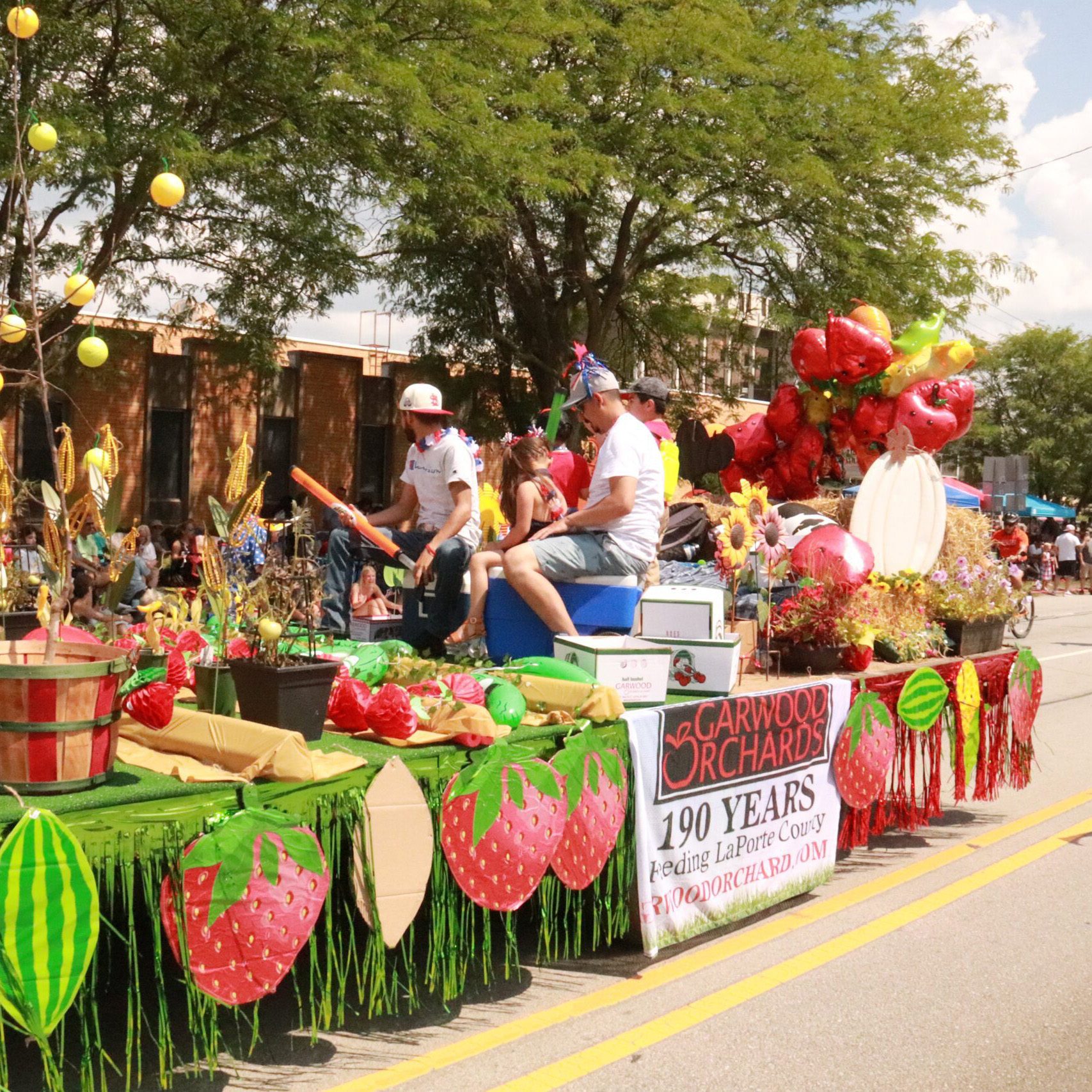 Garwood Orchards float decorated with strawberries, flowers, and farm-themed displays at the Kiwanis Parade in LaPorte, Indiana celebrating community businesses during the Fourth of July parade.